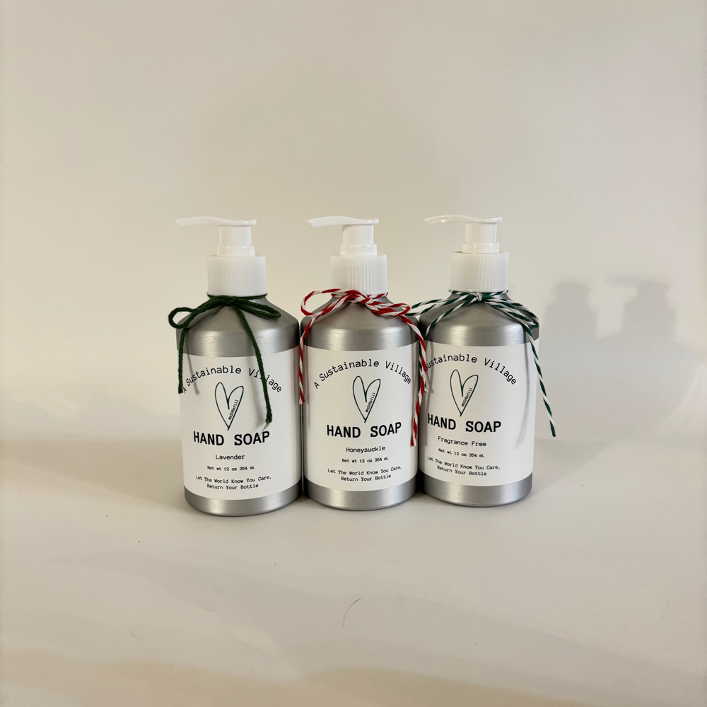 Three aluminum bottles of refillable hand soap with labels on a light background.