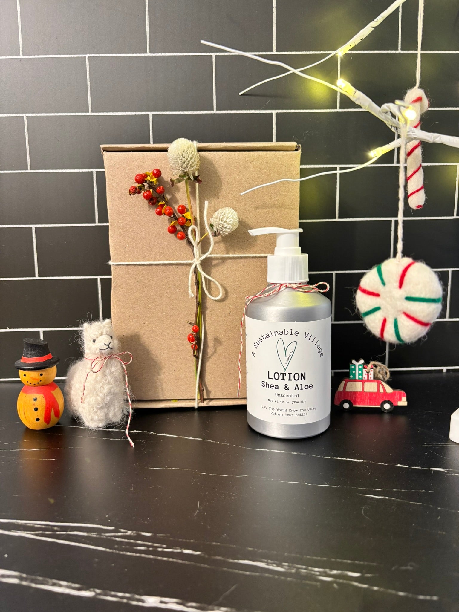 Lotion bottle on a black surface with decorative items and a gift box in the background.