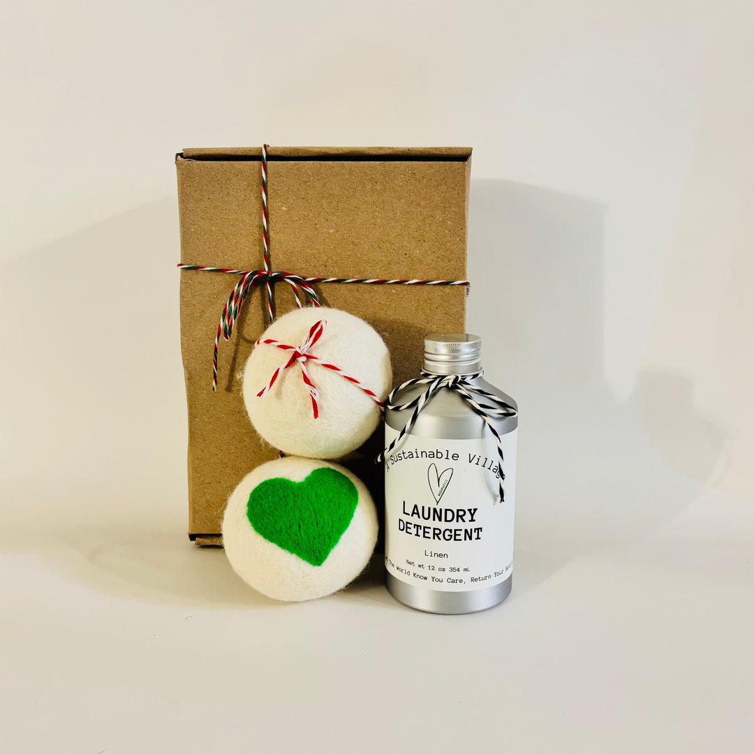 Wool dryer balls with green hearts and a plastic free aluminum bottle of laundry detergent next to a gift box on a light background
