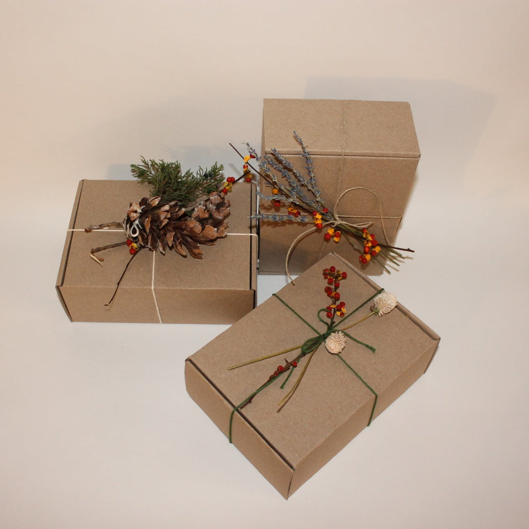 Three brown gift boxes with decorative elements on a white surface